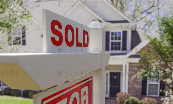 Close-up of sold placard on house for sale real estate sign in front of new house