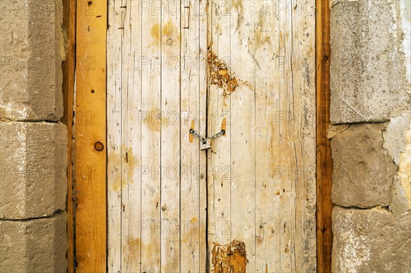 Rusty padlock locking old wooden door with a chain