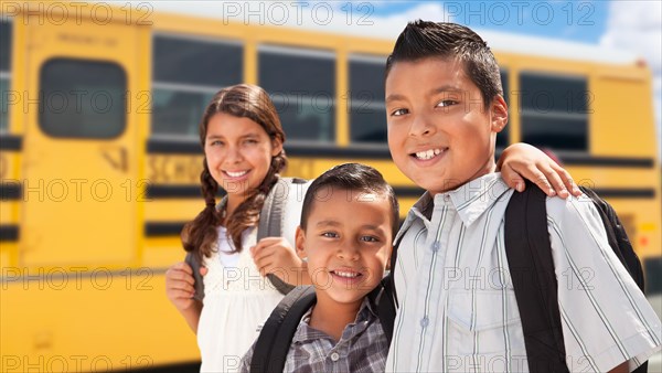 Young hispanic boys and girl walking near school bus