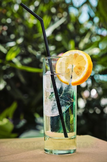 Gin tonic cocktail with lemon and straw on cafe table