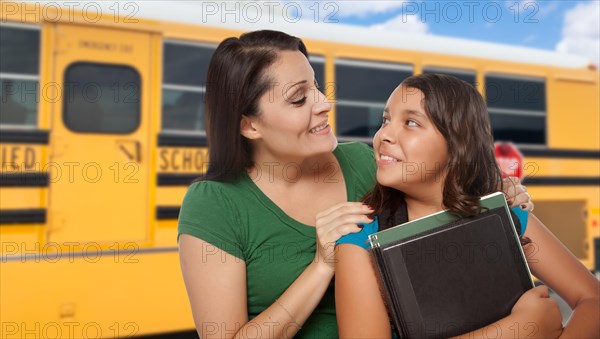 Hispanic mother and daughter near school bus