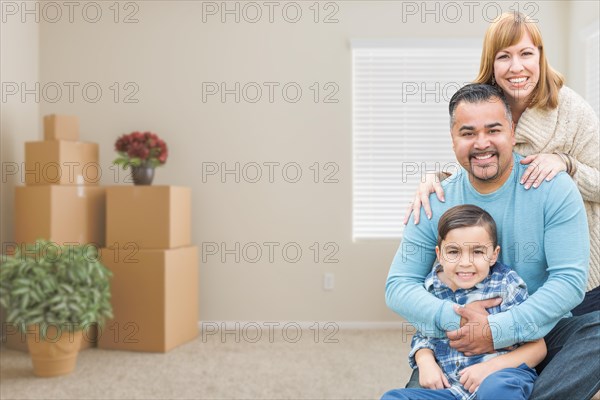 Happy mixed-race family with son in room with packed moving boxes