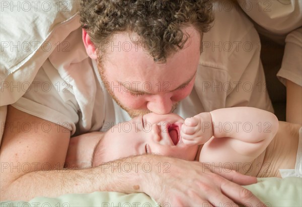 mixed-race chinese and caucasian baby boy laying in bed with his parents