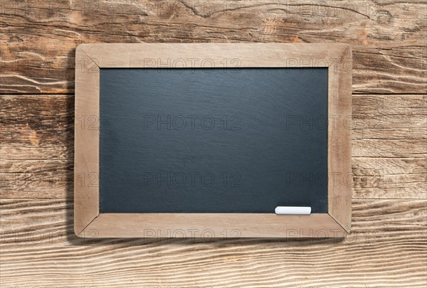 Blank slate black chalkboard with chalk on aged wood background