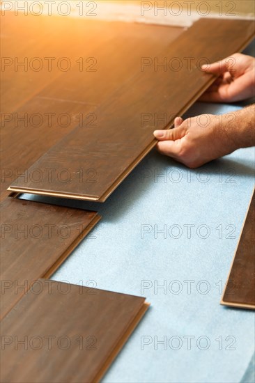 Man installing new laminate wood flooring abstract