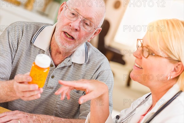 Doctor or nurse explaining prescription medicine to attentive senior man