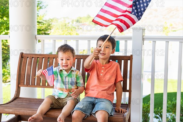 Young mixed-race chinese and caucasian brothers playing with american flags