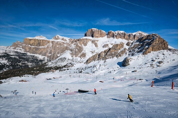 View of a ski resort piste with people skiing in Dolomites in Italy