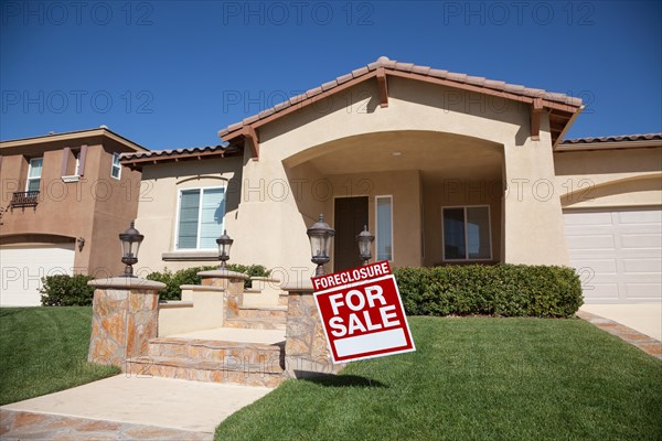 Foreclosure home for sale sign and house with dramatic sky background