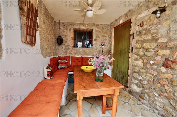 Wooden table with bench in covered dining area with natural stone wall