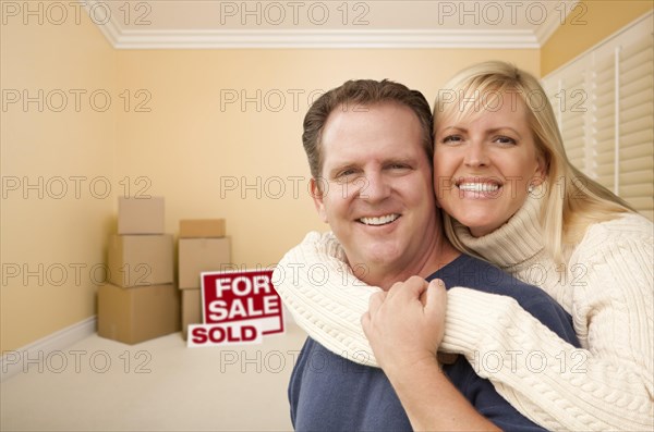 Happy affectionate couple in room of new house with only boxes on the floor