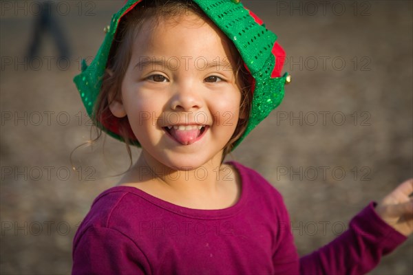 Cute mixed-race young baby girl having fun wearing christmas hat outdoors