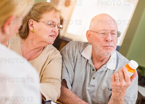Doctor or nurse explaining prescription medicine to senior adult couple