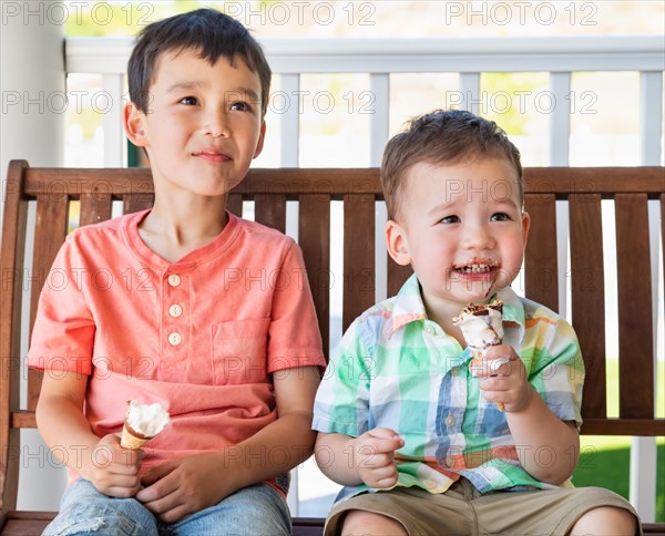 Young mixed-race chinese and caucasian brothers enjoying their ice cream cones