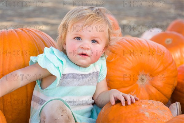 Adorable baby girl having fun in a rustic ranch setting at the pumpkin patch