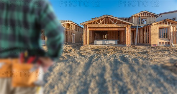 Contractor in front new house wood framing at construction site