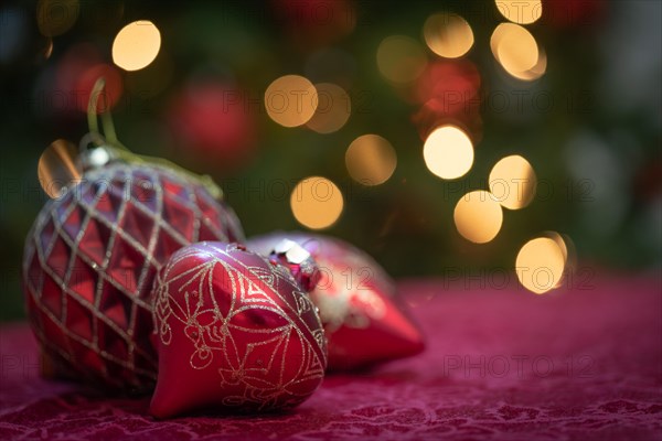 Elaborate christmas ornaments resting on table in front of lit tree