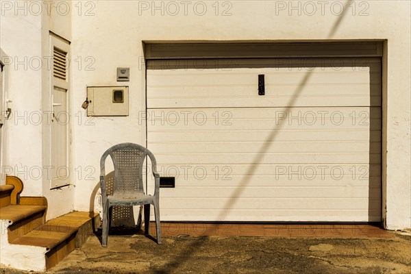 Old dirty plastic chair in front of the garage entrance