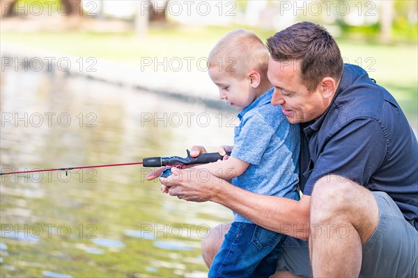 Young caucasian father and son having fun fishing at the lake