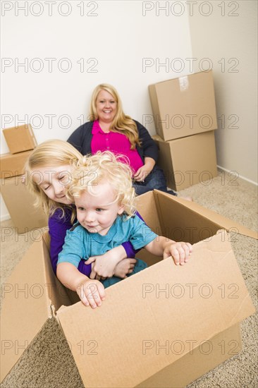 Playful young family in empty room playing with moving boxes