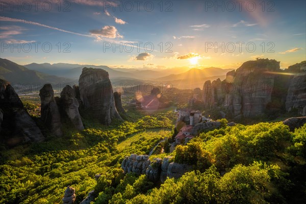 Sunset over monastery of Rousanou and Monastery of St. Nicholas Anapavsa in famous greek tourist destination Meteora in Greece on sunset with sun rays and lens flare