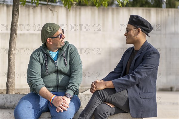 Gay Latino male couple sitting on a bench in a park