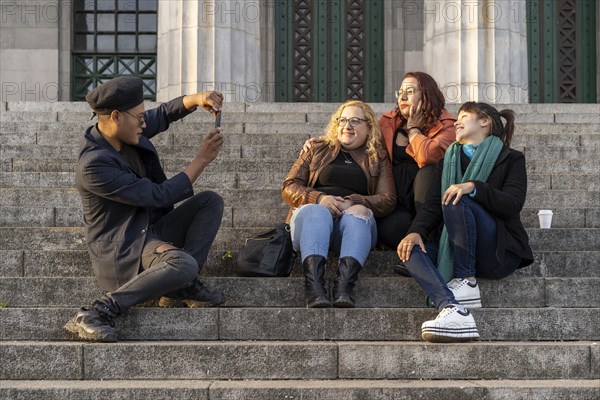 Multi ethnic group of friends sitting on some stairs having a good time chatting