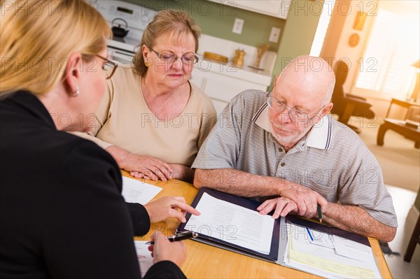 Senior adult couple going over documents in their home with agent at signing