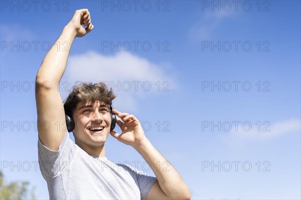 Young man listening to music outdoors with headphones. Expression of happiness