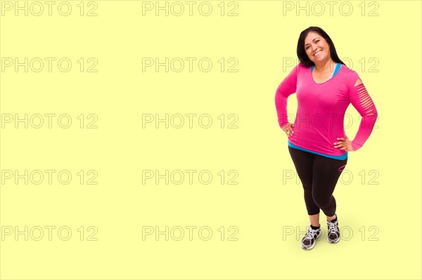 Middle aged hispanic woman in workout clothes against A light yellow background