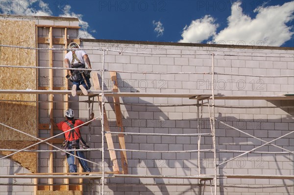 Carpenters working diligently along scaffolding one summer morning