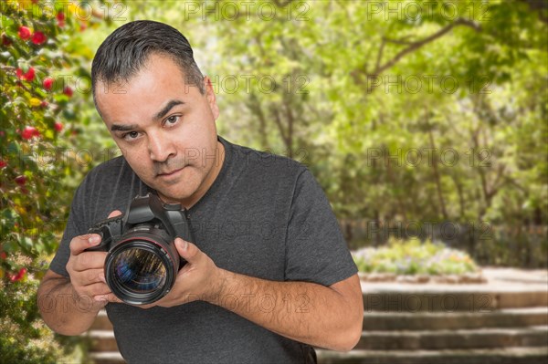 Hispanic young male photographer with DSLR camera outdoors