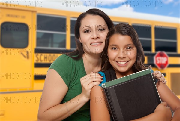 Hispanic mother and daughter near school bus