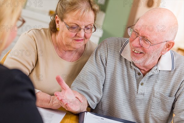 Senior adult couple going over documents in their home with agent at signing