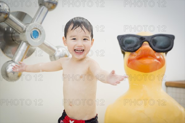 mixed-race boy having fun at the water park with large rubber duck in the background