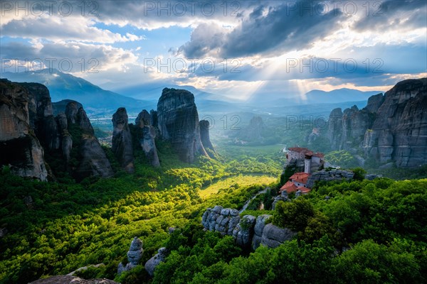 Sunset over monastery of Rousanou and Monastery of St. Nicholas Anapavsa in famous greek tourist destination Meteora in Greece on sunset with sun rays and lens flare and dramatic sky