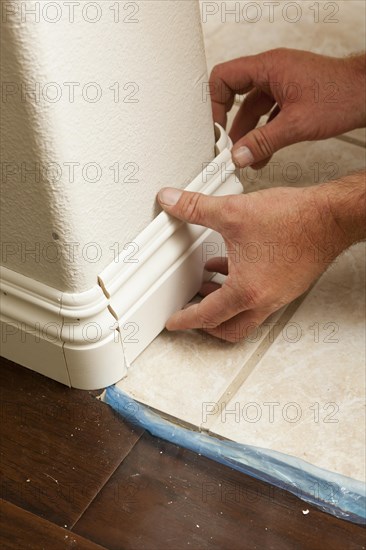 Contractor installing new baseboard with bull nose corners and new laminate flooring renovation abstract