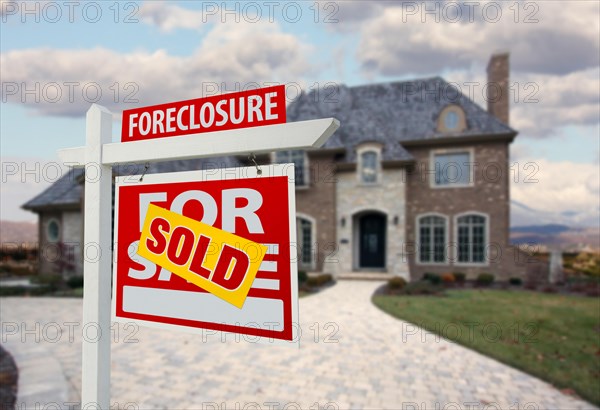 Sold foreclosure home for sale sign and house with dramatic sky background