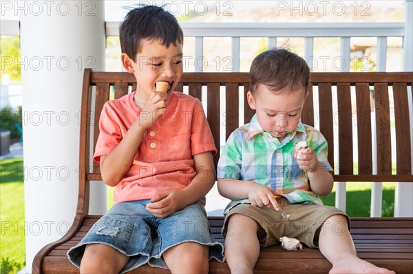 Young mixed-race chinese and caucasian brothers enjoying their ice cream cones