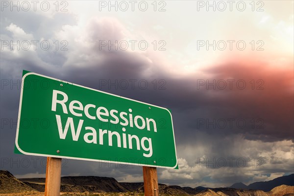 Recession warning green road sign over dramatic clouds and sky