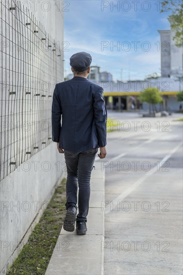 Latin gay male wearing fashion hat doing catwalk in the street