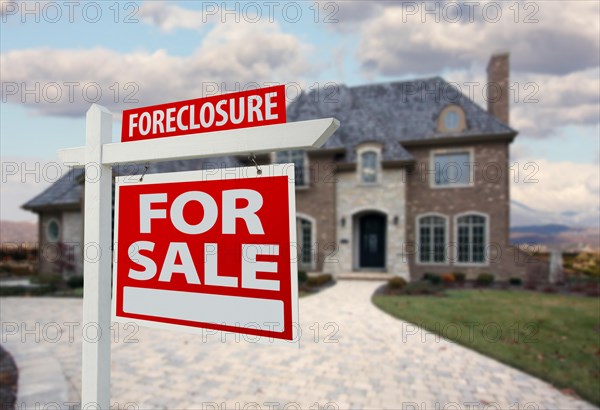 Foreclosure home for sale sign and house with dramatic sky background