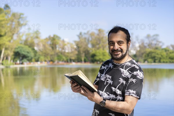 Mature man reading by a lake