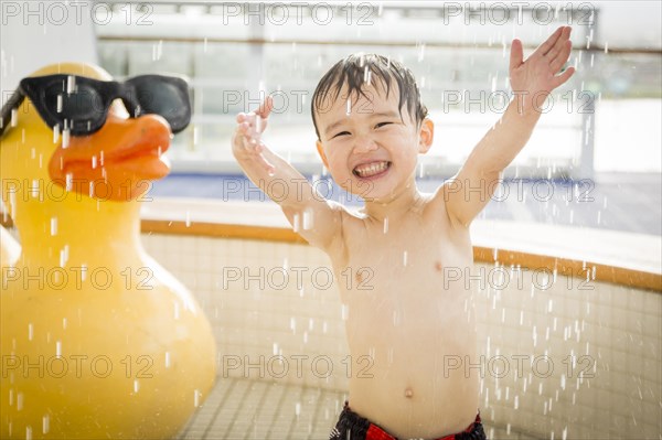 mixed-race boy having fun at the water park with large rubber duck in the background