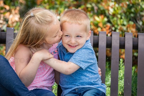 Young sister and brother having fun on the bench at the park