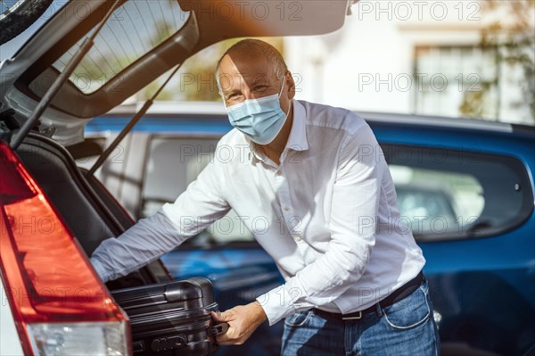 A taxi or Uber driver unloading the luggage from the trunk of his car