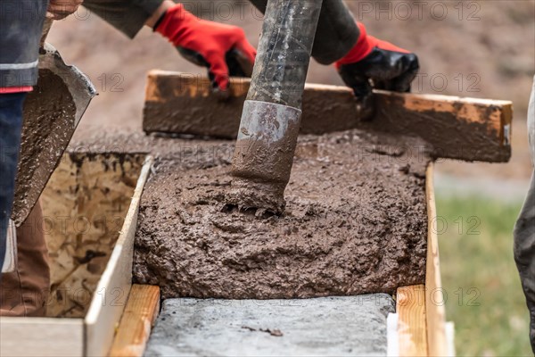 Construction worker leveling wet cement into wood framing