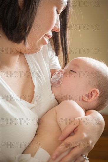 mixed-race chinese and caucasian baby boy being held by his mother