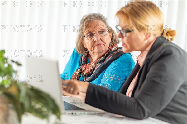 Woman helping senior adult lady on laptop computer