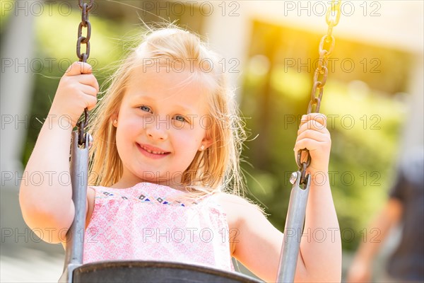 Pretty young girl having fun on the swings at the playground